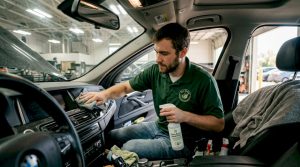 Technician using eco cleaner in car interior