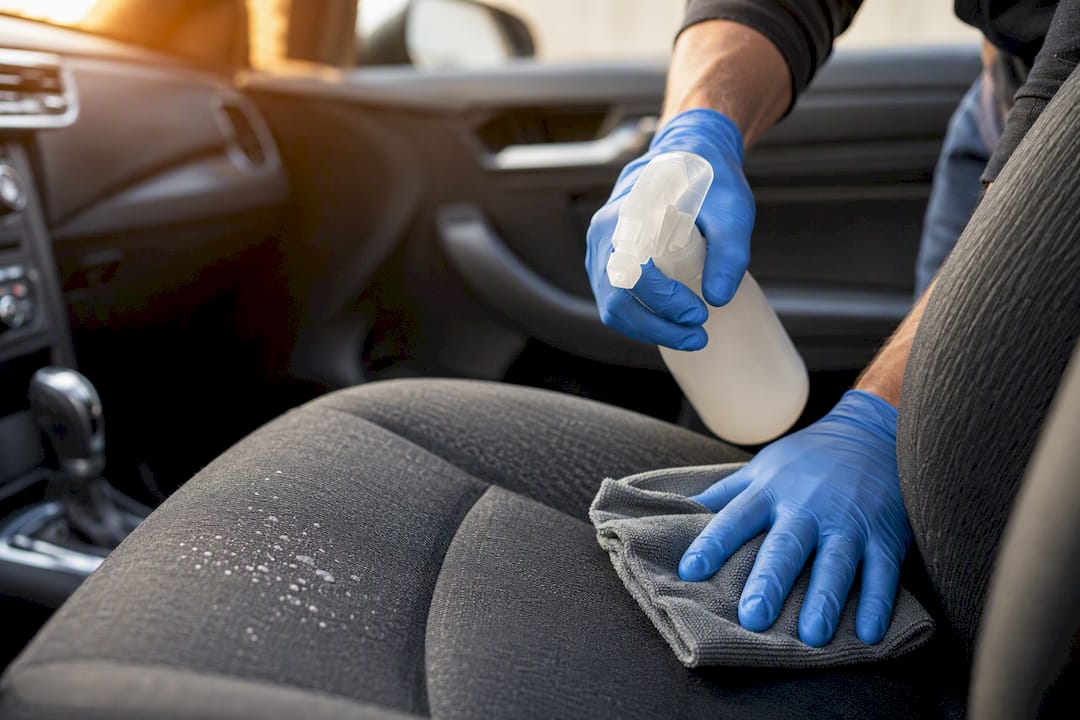 Hands scrubbing car upholstery with eco cleaner
