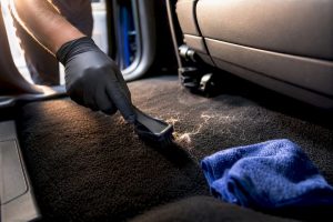 Technician removing dog hair from car carpet