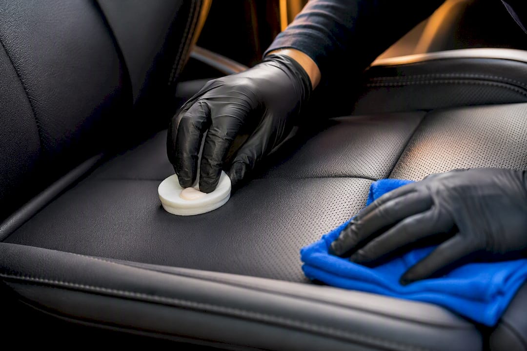 Technician conditioning leather vehicle seat
